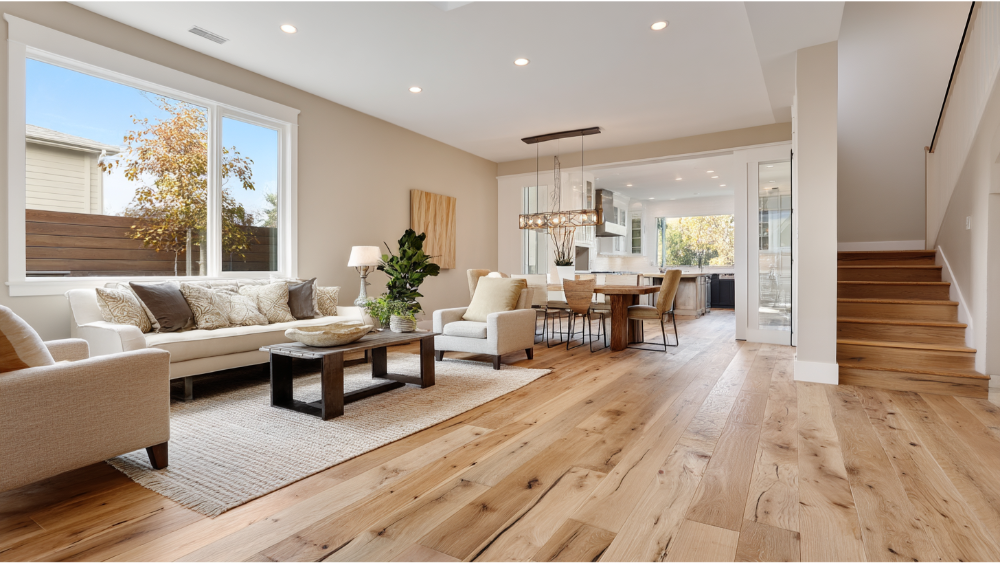 Cozy modern home interior with rustic wide-plank hardwood floors, neutral-toned furniture, and a connected open kitchen and dining space.
