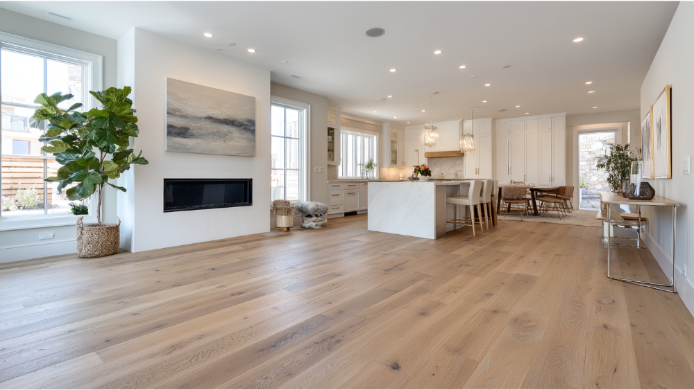Elegant kitchen and dining space featuring wide-plank hardwood floors, marble island, white cabinetry, and large windows for abundant daylight.